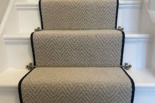 neutral beige herringbone wool carpet stair runner on white wooden staircase with brushed brass stair rods